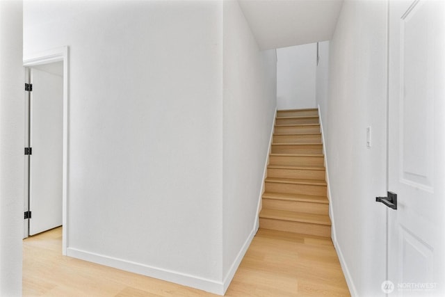 staircase featuring baseboards and wood finished floors