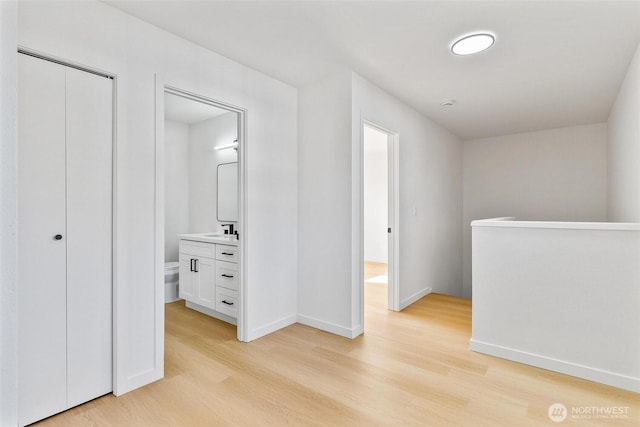 hall with baseboards, an upstairs landing, and light wood finished floors