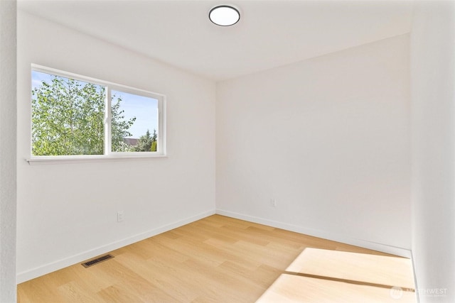 spare room featuring baseboards, visible vents, and light wood-style floors
