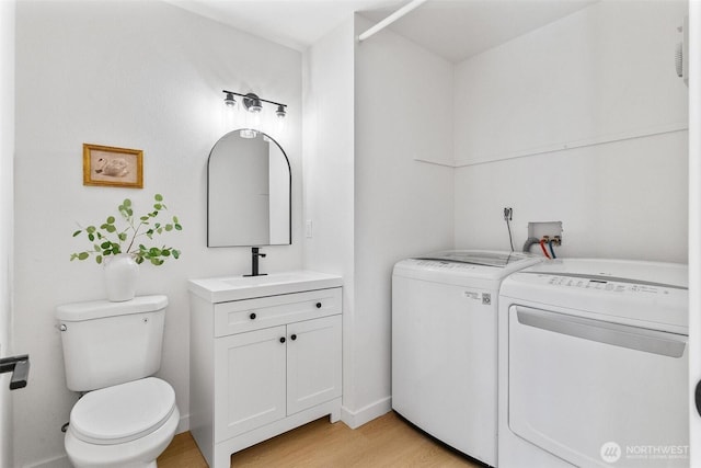 bathroom with wood finished floors, washing machine and dryer, toilet, and vanity