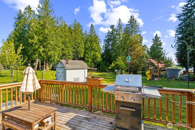 deck featuring an outdoor structure, a lawn, grilling area, and a shed