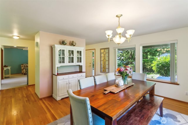 dining space featuring an inviting chandelier, baseboards, and light wood-type flooring