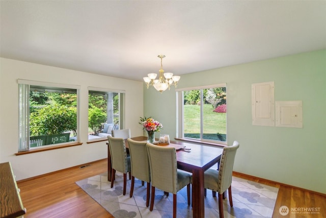 dining space featuring baseboards, an inviting chandelier, a healthy amount of sunlight, and light wood-style flooring
