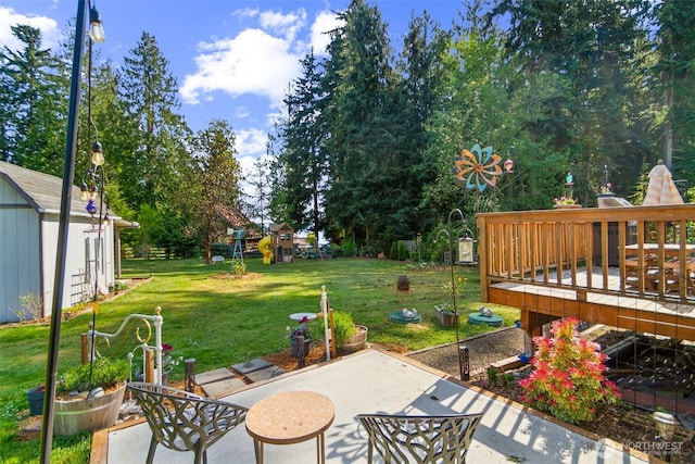 view of yard featuring a storage shed, a patio, an outdoor structure, and a deck
