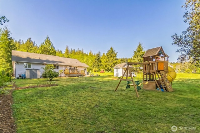 view of yard with a storage unit, a playground, a wooden deck, and an outbuilding
