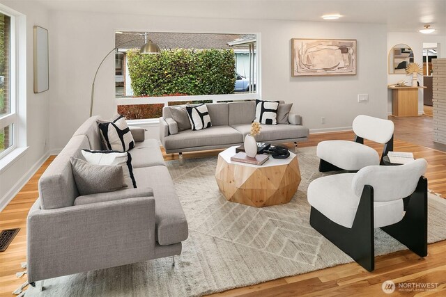 living area featuring baseboards, wood finished floors, and visible vents