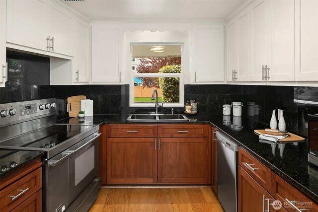 kitchen with a sink, appliances with stainless steel finishes, decorative backsplash, and white cabinetry