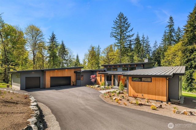 view of front of property with aphalt driveway, a standing seam roof, metal roof, and a garage