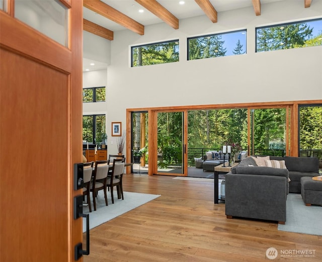 living room featuring beamed ceiling, a high ceiling, and wood finished floors