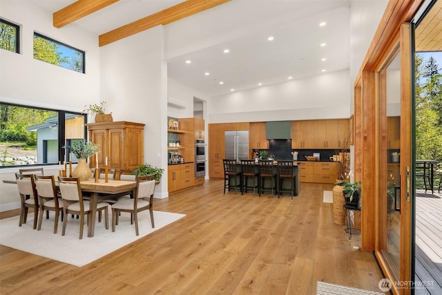 dining room with a healthy amount of sunlight, a high ceiling, light wood-type flooring, and recessed lighting