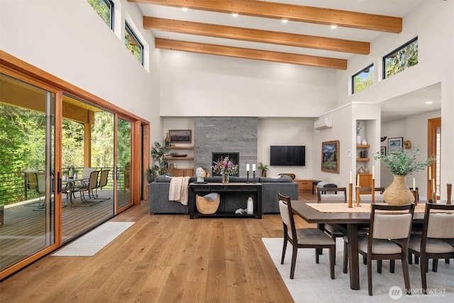 dining area with a high ceiling, a wall mounted air conditioner, beam ceiling, and light wood-style floors