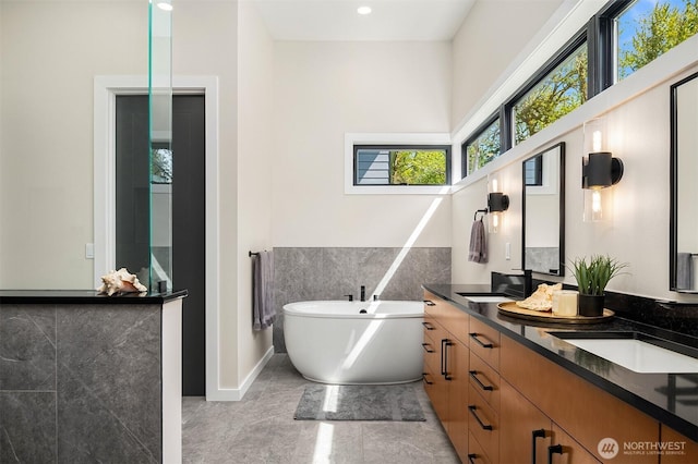 full bath featuring double vanity, a freestanding bath, and a sink