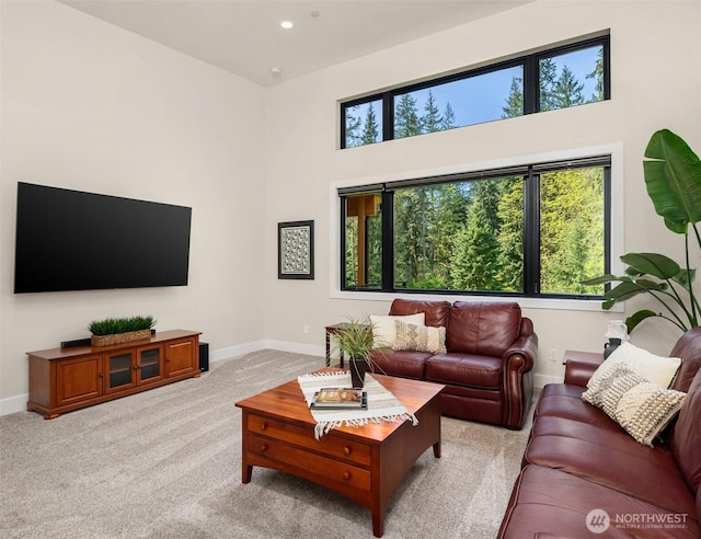 living room with baseboards, recessed lighting, a towering ceiling, and light carpet