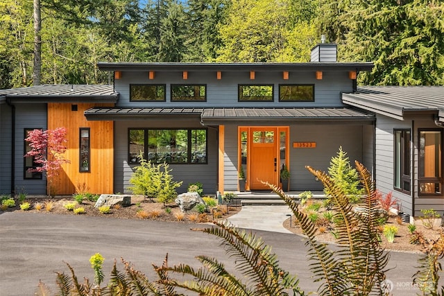 view of front facade with a standing seam roof, a chimney, and metal roof