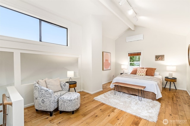 bedroom with an AC wall unit, beamed ceiling, track lighting, and hardwood / wood-style flooring
