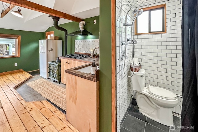 bathroom featuring vaulted ceiling, backsplash, a wealth of natural light, and toilet