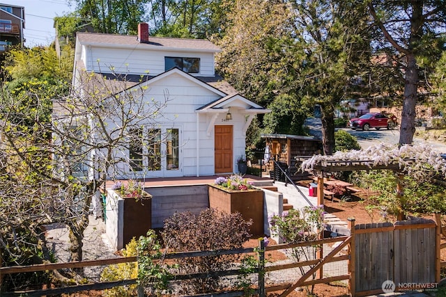 view of front of home featuring fence private yard, roof with shingles, and a chimney