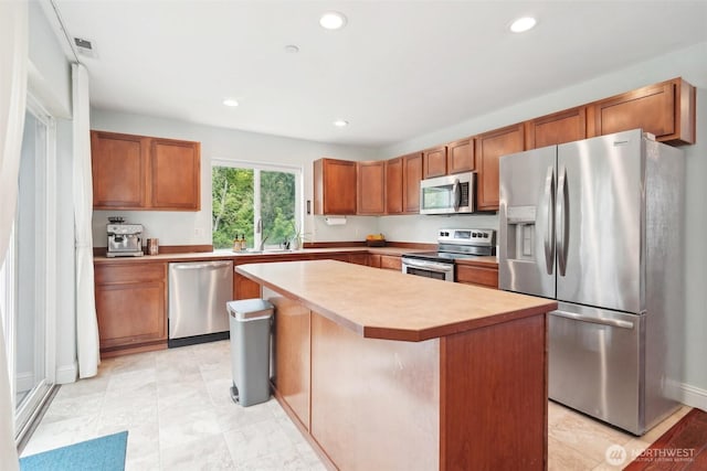 kitchen with a kitchen island, stainless steel appliances, recessed lighting, and brown cabinetry
