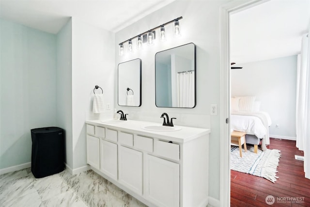 ensuite bathroom featuring a sink, baseboards, ensuite bathroom, and double vanity