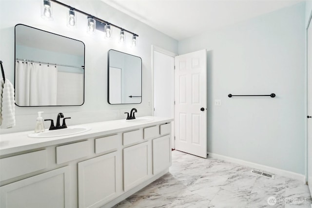 full bath with baseboards, a sink, marble finish floor, and double vanity