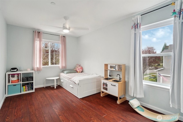 bedroom featuring baseboards, ceiling fan, dark wood-style floors, and a sink
