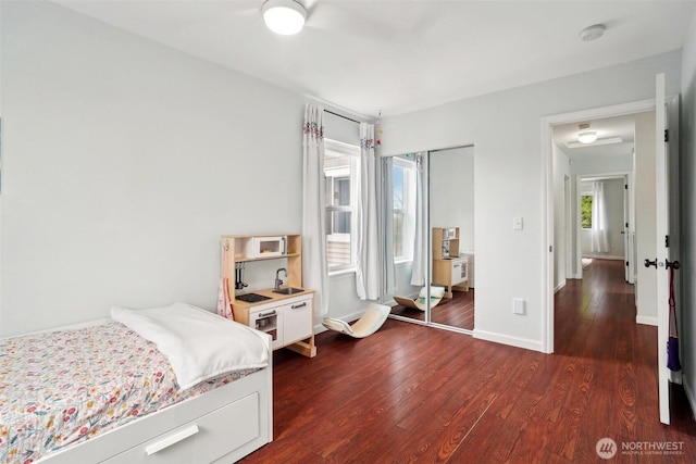 bedroom with baseboards, a closet, and dark wood-type flooring