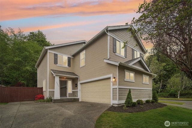 view of front of property featuring concrete driveway, an attached garage, fence, and a yard