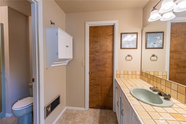bathroom with vanity, baseboards, backsplash, and toilet