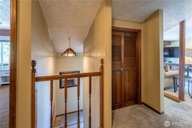 hallway with baseboards, a textured ceiling, and carpet