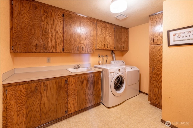 laundry area featuring visible vents, cabinet space, a sink, light floors, and separate washer and dryer