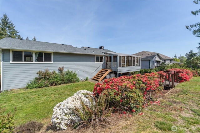 back of property with a sunroom, a shingled roof, a lawn, and stairs