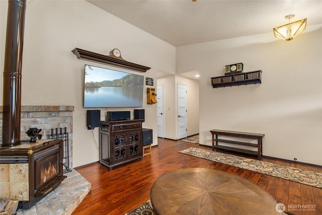 living area with a wood stove, hardwood / wood-style flooring, and lofted ceiling