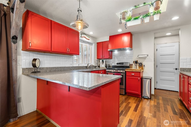 kitchen featuring decorative backsplash, a peninsula, wood finished floors, wall chimney exhaust hood, and stainless steel range with gas stovetop