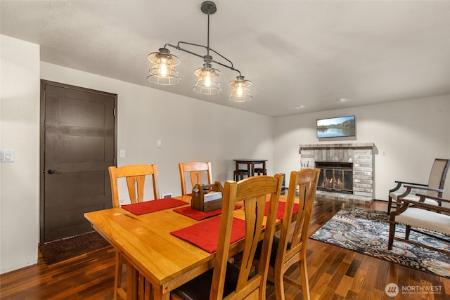 dining room featuring a glass covered fireplace and wood finished floors