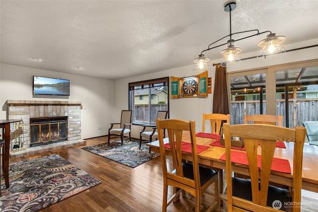 dining room with a textured ceiling, a fireplace, and hardwood / wood-style flooring