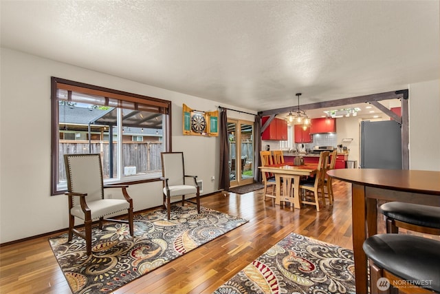 living room with baseboards, a textured ceiling, wood finished floors, and a notable chandelier