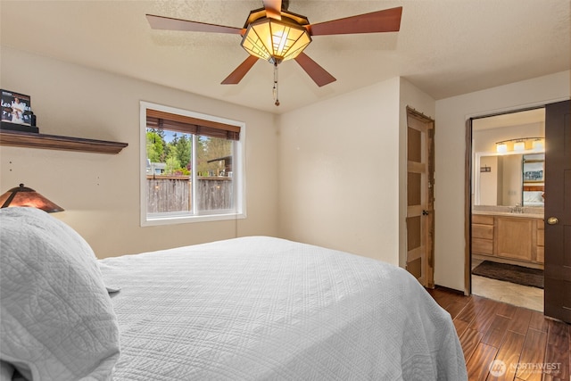 bedroom with a sink, a ceiling fan, ensuite bath, and dark wood-type flooring