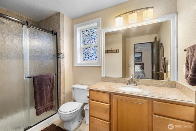 full bath featuring vanity, a stall shower, and toilet
