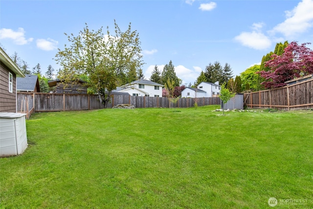 view of yard featuring a residential view, an outbuilding, a fenced backyard, and a shed