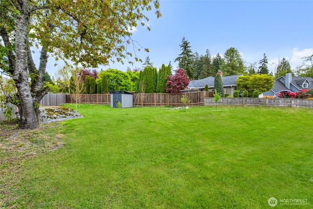 view of yard with an outbuilding, a fenced backyard, and a shed