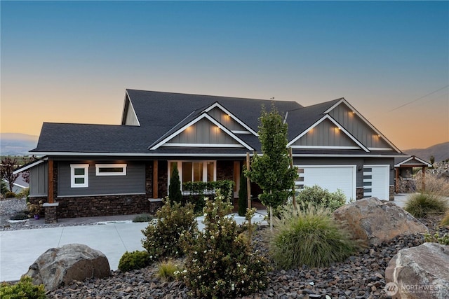craftsman house with a garage, stone siding, roof with shingles, board and batten siding, and concrete driveway