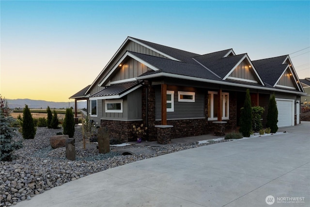 craftsman-style home featuring board and batten siding, a porch, a garage, concrete driveway, and stone siding