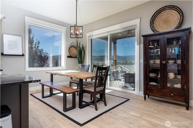 dining room with baseboards, light wood finished floors, and a chandelier
