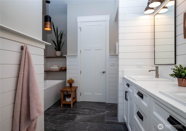 bathroom with double vanity, a sink, a tub to relax in, and marble finish floor