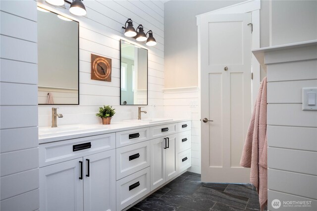 full bathroom with a sink, wooden walls, and marble finish floor