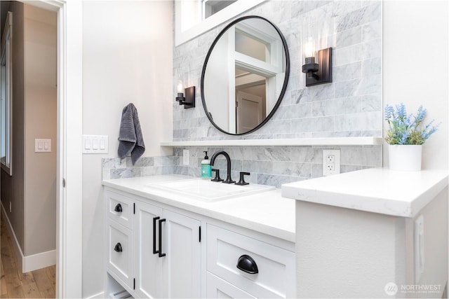 bathroom with wood finished floors, baseboards, backsplash, and vanity
