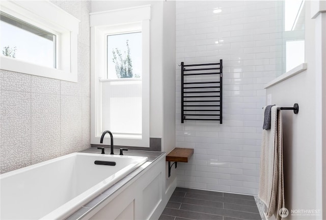 bathroom featuring tile patterned flooring, tile walls, and a bath