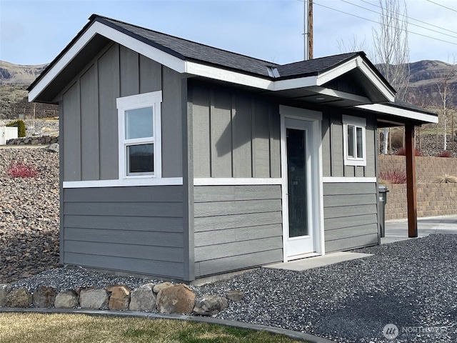 view of home's exterior with fence, a mountain view, board and batten siding, and an outbuilding