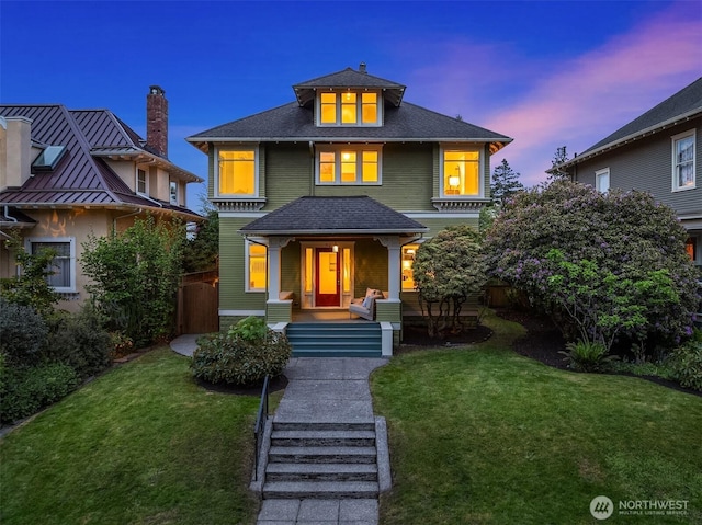 american foursquare style home with a chimney, a front lawn, and covered porch