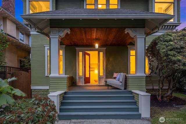 entrance to property with a porch and fence
